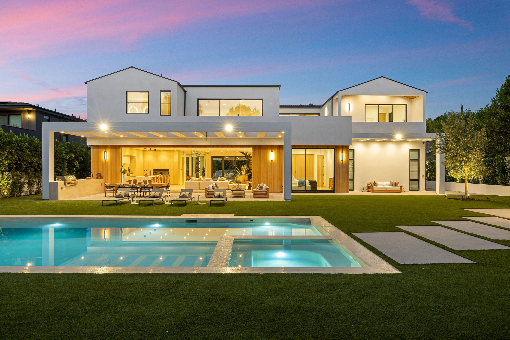 Modern luxury home with pool at sunset.